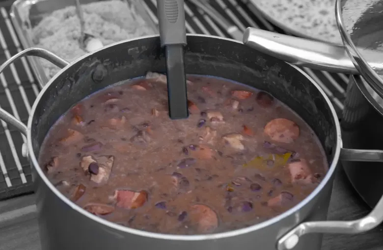 A pan of feijoada, the Brazilian black bean stew, with pieces of pork and sausage through it.