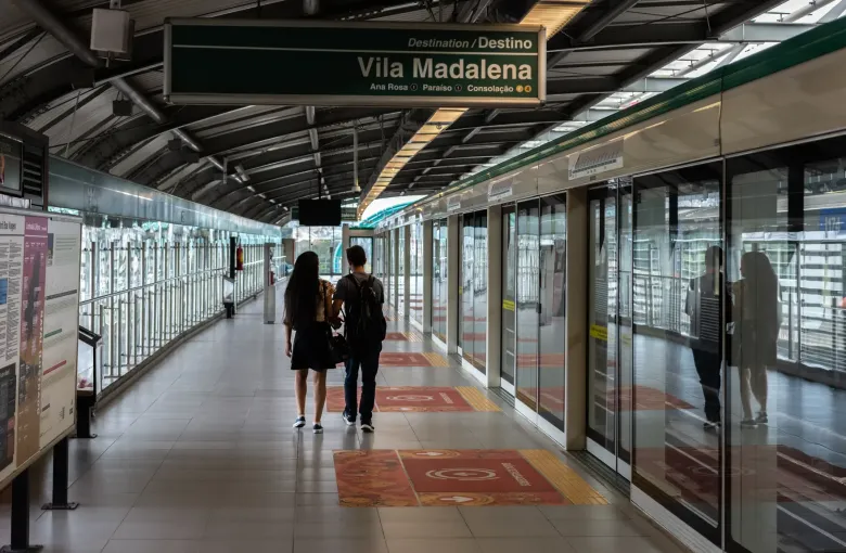 A Sao Paulo Metro platform with platform-edge doors, overhead destination signs and passengers waiting.