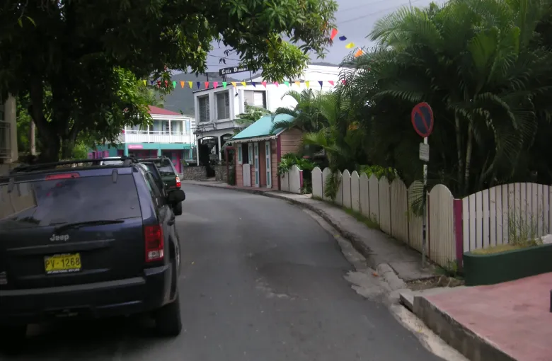 Main Street in Road Town, Tortola: parked cars, bunting overhead, and pastel buildings behind a picket fence.
