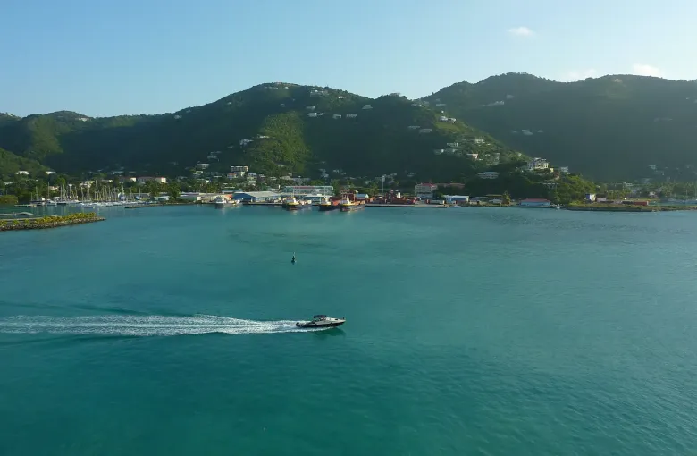 Road Town on Tortola seen across the water, the capital spread along the shore beneath green ridges.