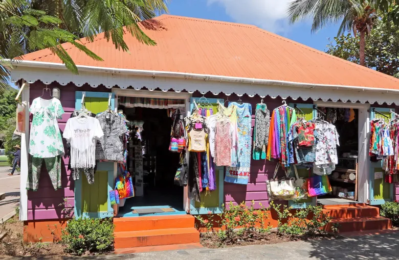 A pink and orange wooden souvenir shop on Tortola with printed clothing hanging across its front.