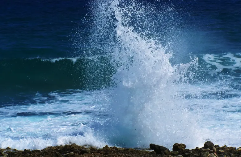 White spray bursting through the ironshore at the East End blow holes on Grand Cayman, against deep blue sea.