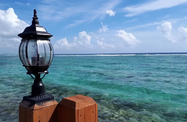 A black lamp post on a timber dock at George Town, with pale reef shallows and the open sea beyond.