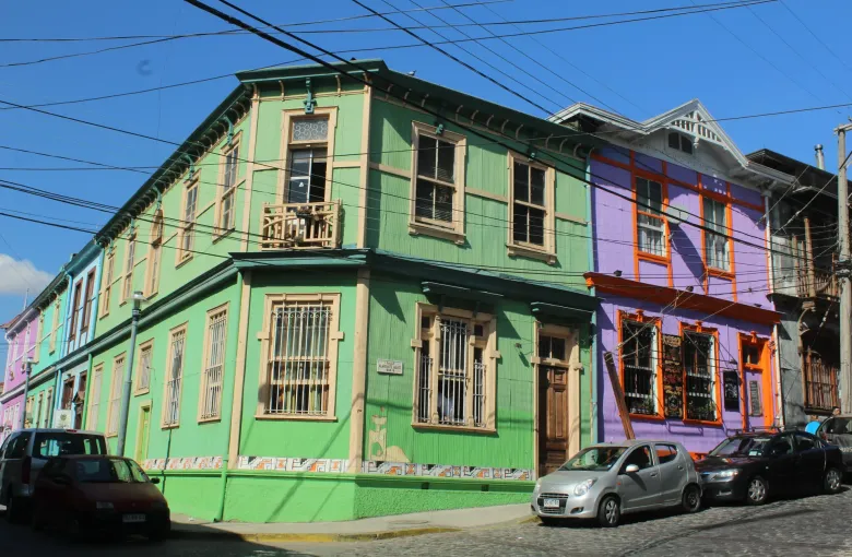 A corner of painted corrugated iron houses in green and purple on a cobbled street in the hills of Valparaiso.
