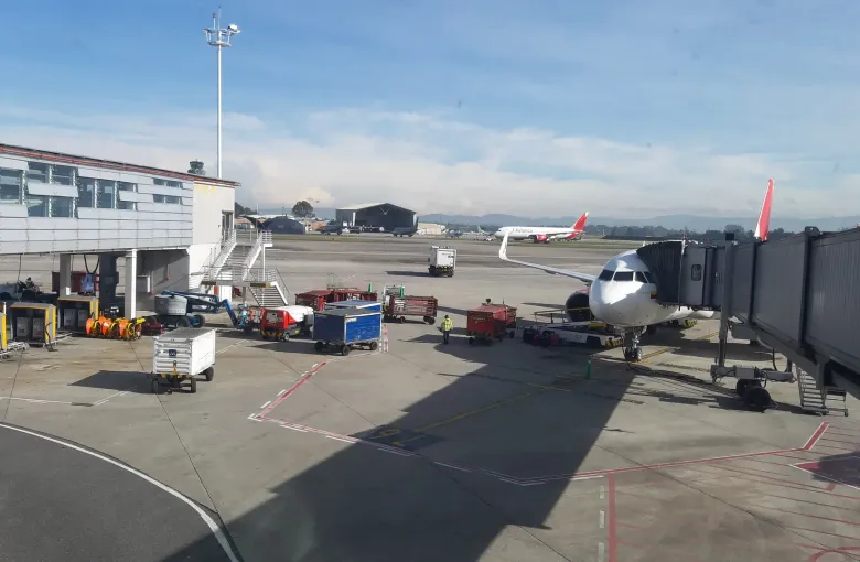 Aircraft parked at jet bridges on the apron at El Dorado International Airport in Bogota, ground vehicles below them.