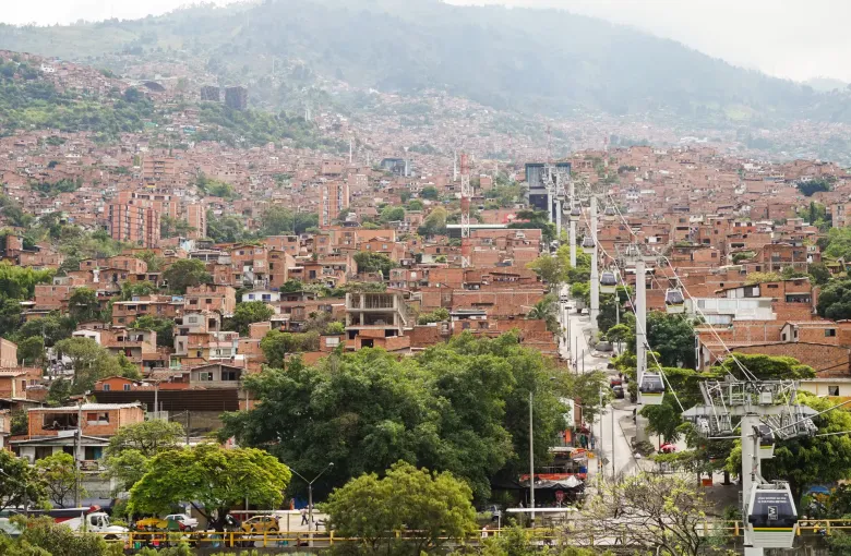 The Medellin valley with Metrocable towers and cables running up the hillside above densely built neighborhoods.