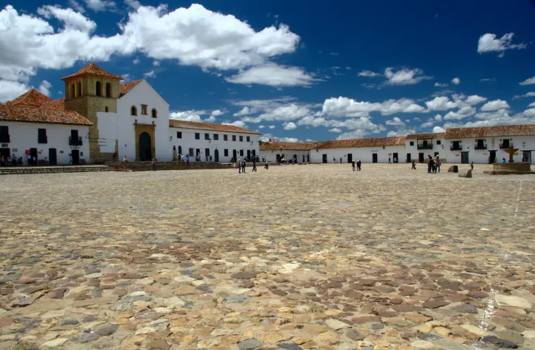 The vast cobbled main plaza of Villa de Leyva with its white church on the far side and low whitewashed buildings around it.