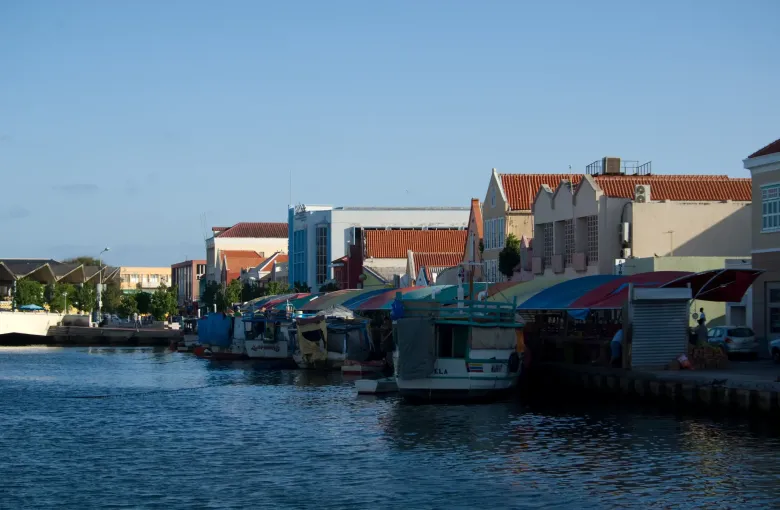 Boats moored at the floating market in Willemstad, awnings shading stalls of produce.