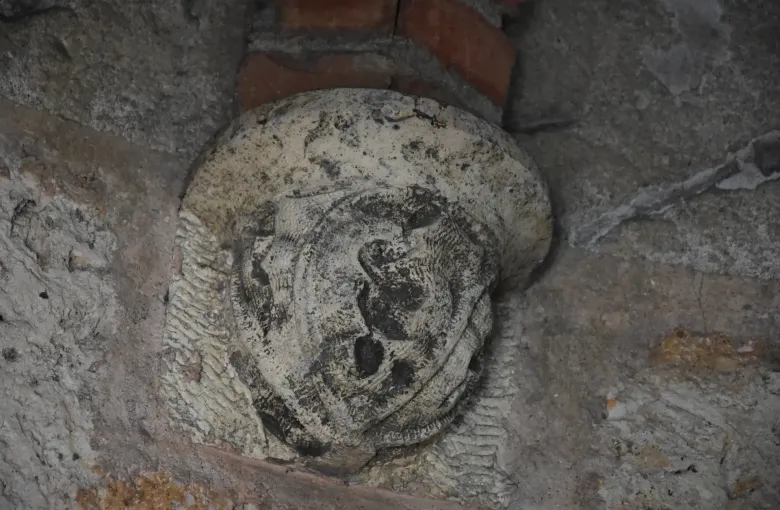 A weathered carved stone corbel set into a brick and masonry wall at the Alcazar de Colon in Santo Domingo.