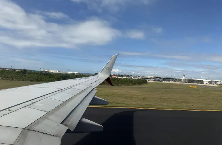 The wing of an aircraft on approach over the airfield at Las Americas International Airport.