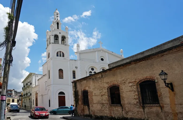 A white bell tower and church front on a narrow street in the Colonial City of Santo Domingo.