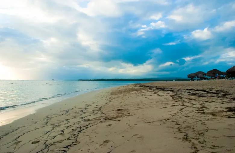 A wide, level stretch of sand at Playa Dorada near Puerto Plata, with calm water and soft afternoon light.