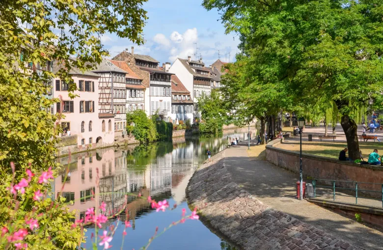 A cobbled quay beside the water in the Petite France quarter of Strasbourg, with timbered houses and window flowers.