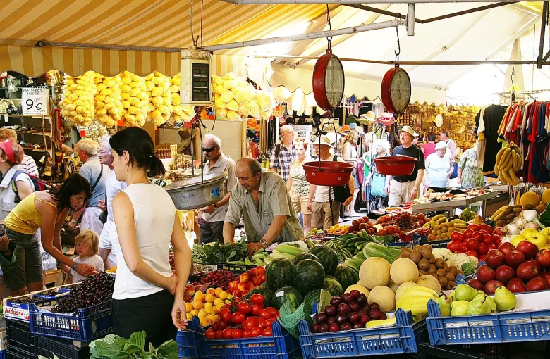 Crates of tomatoes, melons and cherries under a striped awning at the produce market in Heraklion, Crete, Greece.