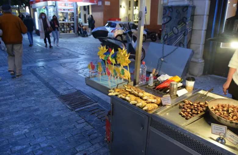 Roast corn and chestnuts with euro price cards on a street food cart on an Athens pavement at dusk, Greece.