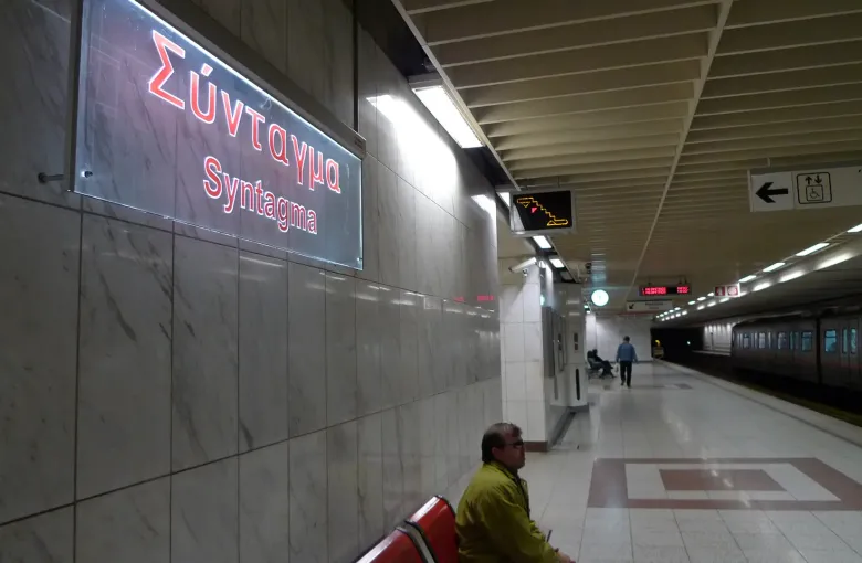 The bilingual Syntagma platform sign and a waiting train at Syntagma metro station in Athens, Greece.