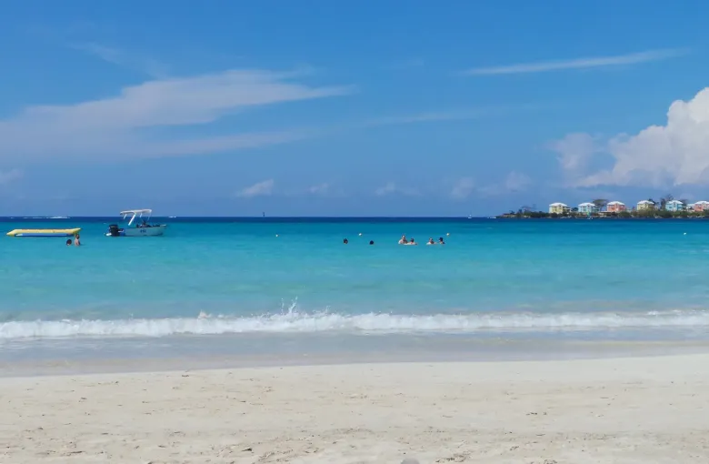 Calm turquoise water meets white sand at Bloody Bay in Negril under a clear sky.