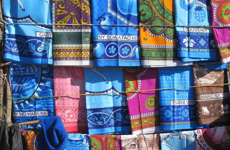 Brightly printed cotton lamba cloths hanging on a market stall in Madagascar.