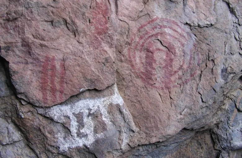 Red and white paintings on a weathered granite rock face in the Chongoni Rock-Art Area, Malawi, including animal figures and geometric marks.