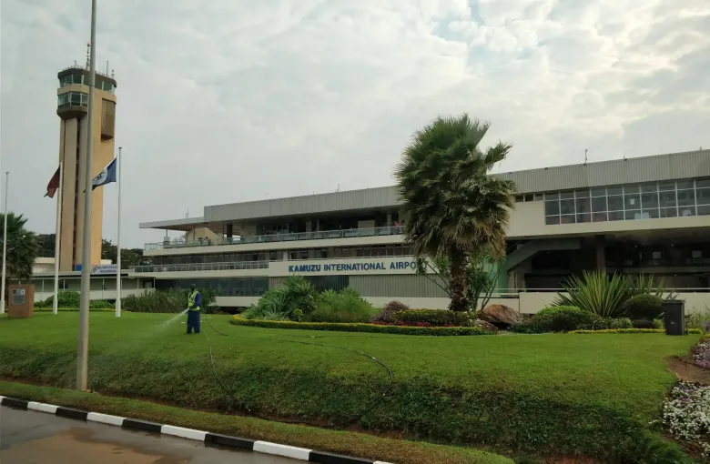 The terminal and control tower of Kamuzu International Airport at Lilongwe, Malawi, seen across a lawn and an approach road.