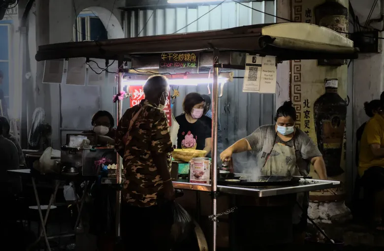A hawker cooks char koay kak over a wok at a street stall on Jalan Chulia in George Town, Penang.