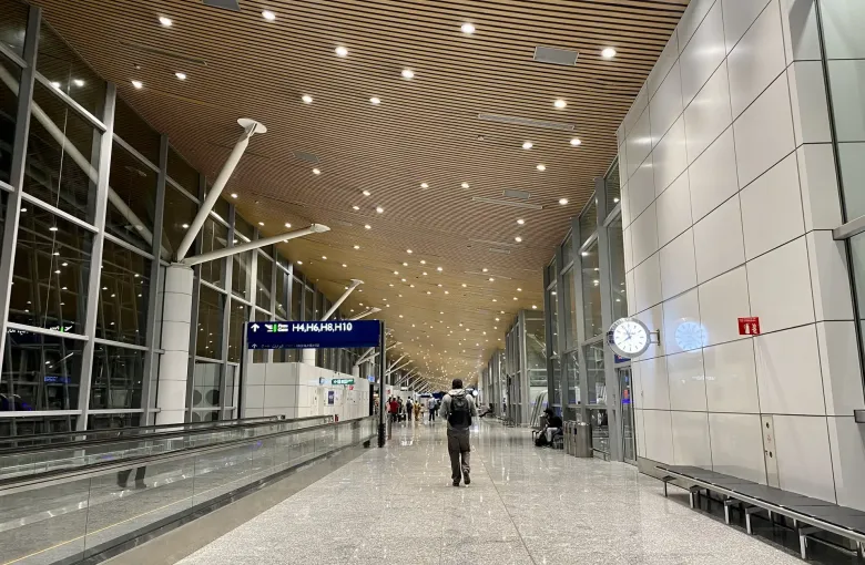 A long, bright concourse at Kuala Lumpur International Airport Terminal 1 with a few distant travelers.