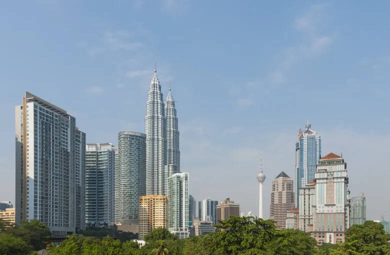 The Kuala Lumpur skyline with the Petronas Twin Towers and KL Tower under a wide bank of cloud.