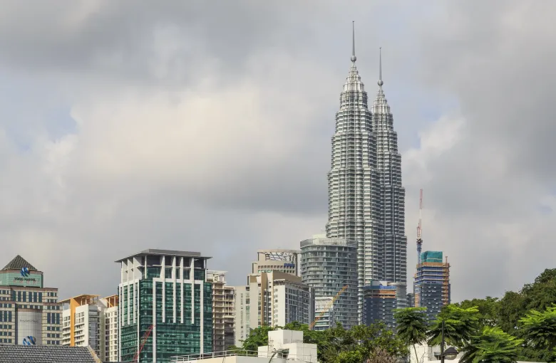 The Petronas Twin Towers rising above office blocks and trees in central Kuala Lumpur.