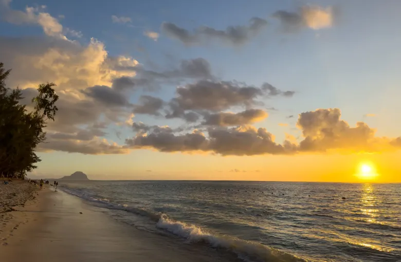 The sun low over a calm sea from the shore at Flic en Flac on the west coast of Mauritius.