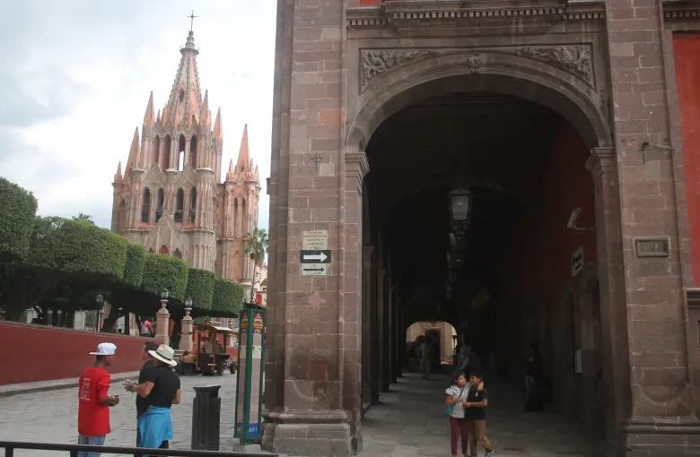 The pink spires of the Parroquia de San Miguel Arcangel seen from under the arcade of the portales in San Miguel de Allende.
