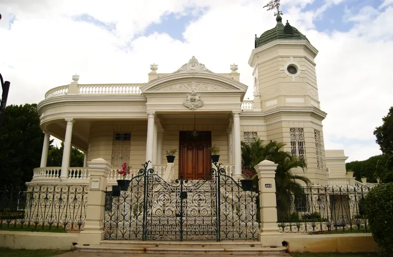 The white portico and iron gates of the Quinta Montes Molina, a preserved mansion on the Paseo de Montejo in Merida.