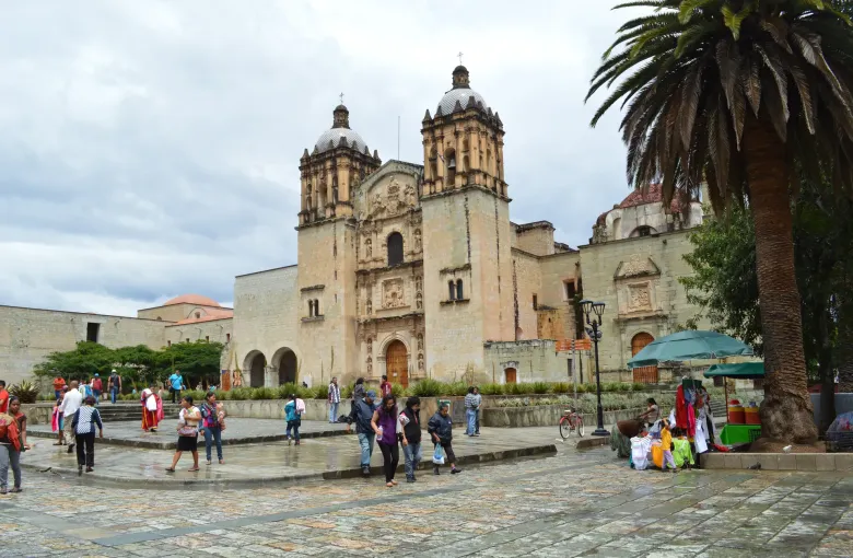 The twin bell towers and carved stone front of Santo Domingo de Guzman in Oaxaca, with the planted forecourt below.