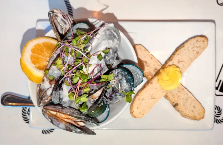 A bowl of New Zealand green lipped mussels in coconut milk served with buttered bread.
