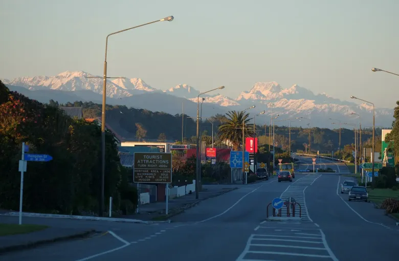 Snow covered peaks of the Southern Alps seen at the end of an ordinary main street in Hokitika.
