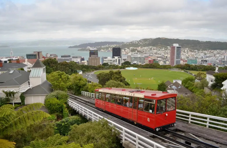 The red Wellington Cable Car climbing its track toward Kelburn above the city and the harbor.