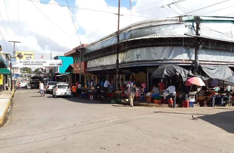 Stalls and crates spread onto the street at a corner market in Bluefields where traders sell under tarpaulins.