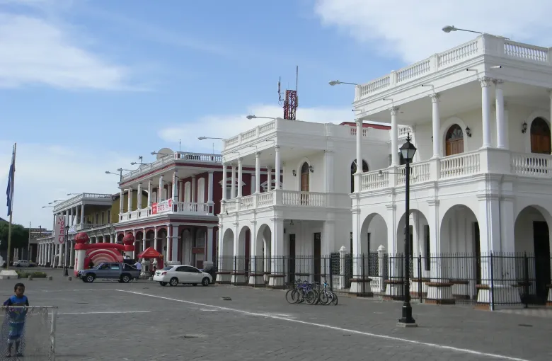 The Nicaraguan flag flies beside the colonnaded colonial buildings lining the main plaza in Granada.