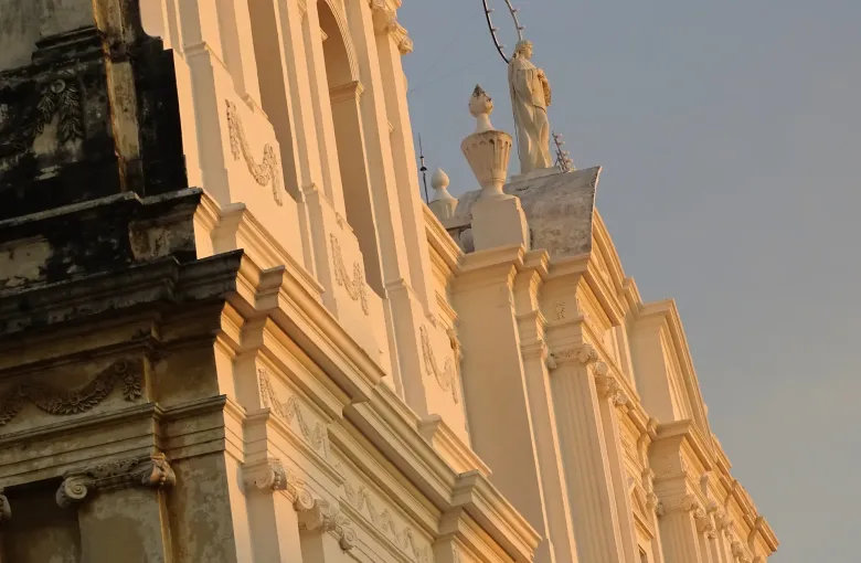 Evening light warms the carved cornices of Leon Cathedral, where a haloed statue of the Virgin crowns the roofline.