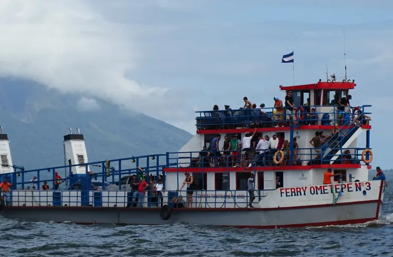 Passengers crowd the open decks of a ferry flying the Nicaraguan flag as it crosses Lake Nicaragua to Ometepe.
