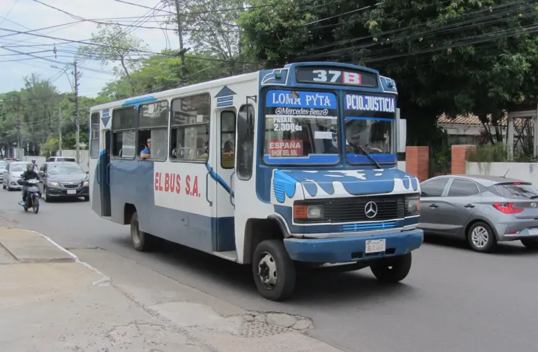 A blue and white colectivo bound for Loma Pyta turns onto a residential street in Asuncion.