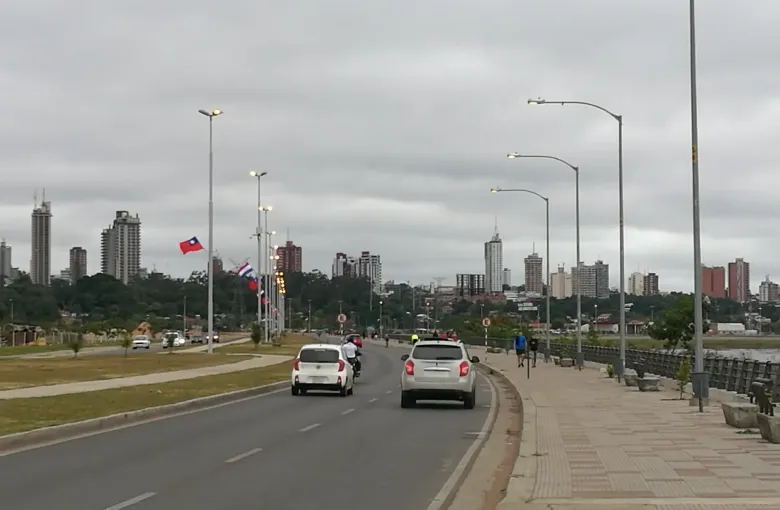 The Costanera avenue curves along the bay at Asuncion with the city skyline standing on the ridge beyond.