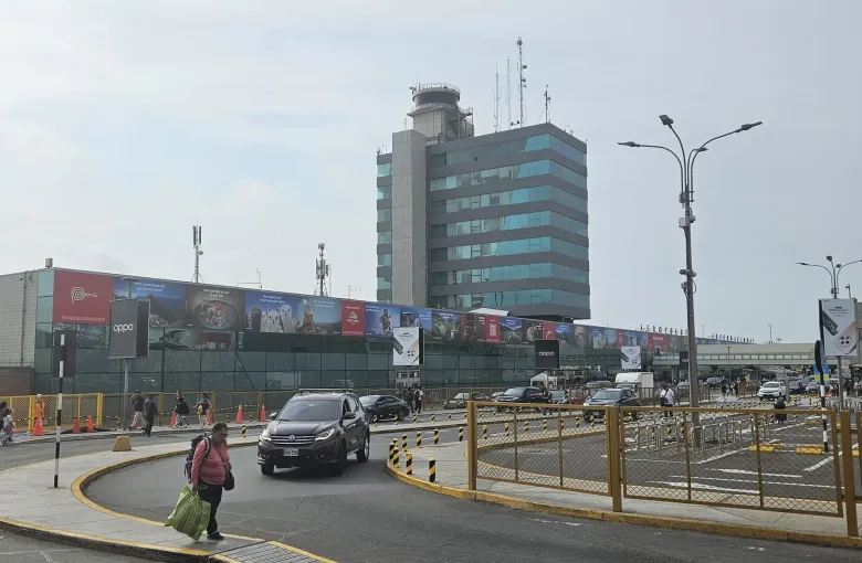 The terminal frontage and control tower of Jorge Chavez International Airport in Lima with traffic on the access road.