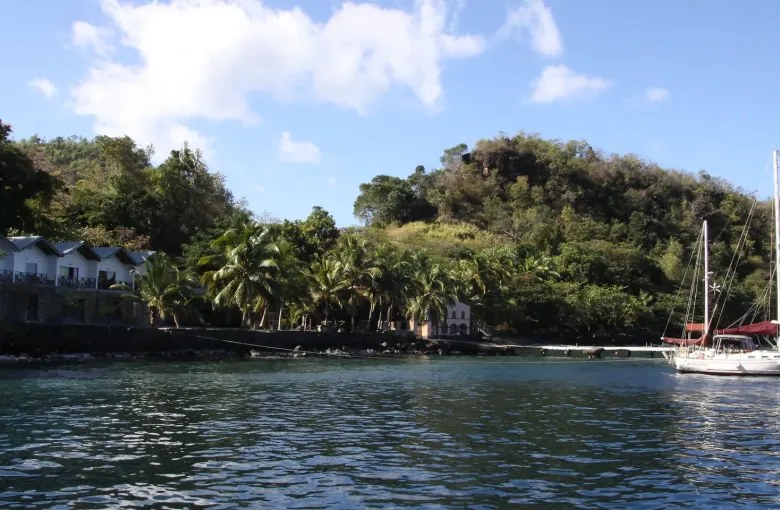 A yacht at anchor below the palms and green hillsides of Wallilabou Bay in Saint Vincent.