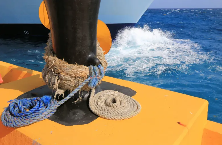 A mooring rope coiled around a bollard on the cruise pier, open sea beyond.