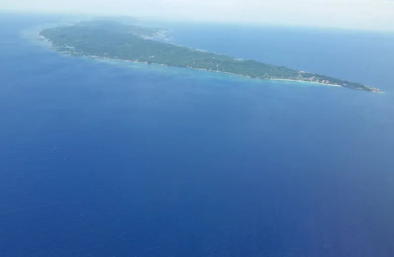 The long wooded ridge of Roatan seen from the air across open water.