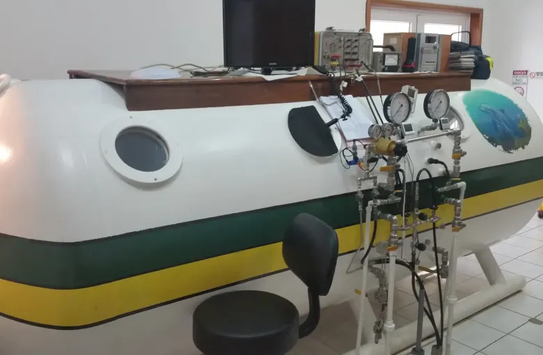 A hyperbaric recompression chamber with its control gauges, inside a treatment room.