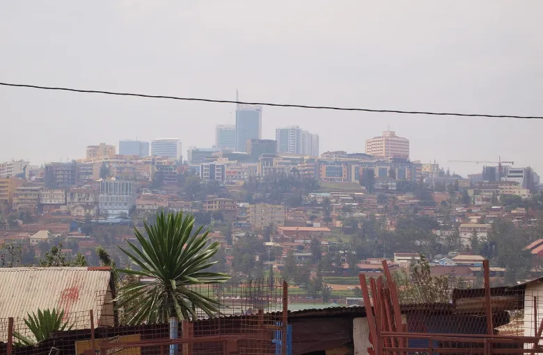 Kigali across a valley, with downtown towers along the ridge and dense housing on the slopes below, seen from the grounds of the Genocide Memorial.