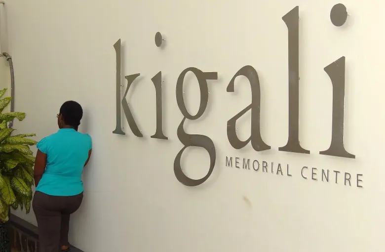 A visitor stands at the wall sign reading Kigali Memorial Centre at the genocide memorial in Kigali, Rwanda.