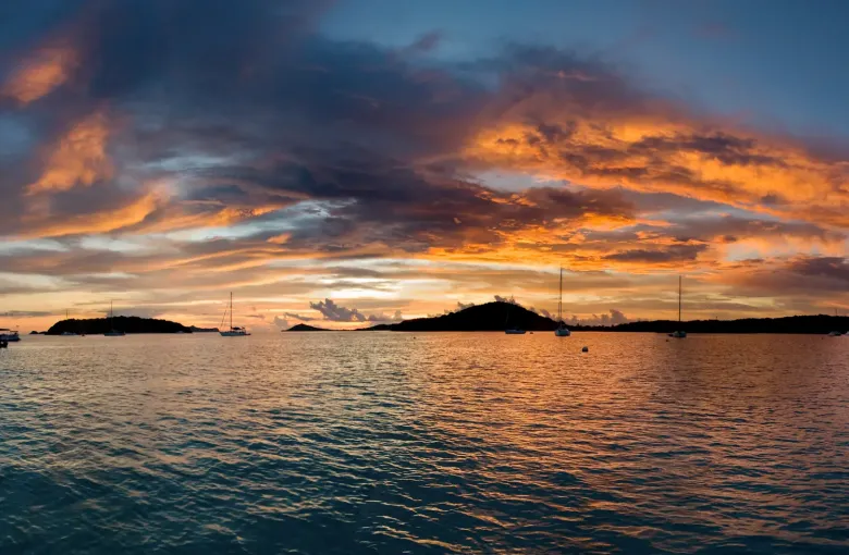 Yachts at anchor at sunset off the low islands of the Tobago Cays.