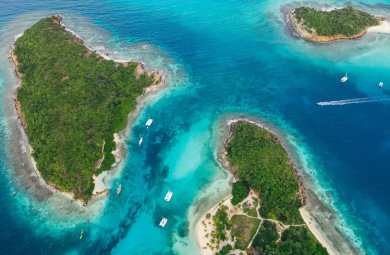 Yachts anchored on turquoise shallows between the low green islands of the Tobago Cays.